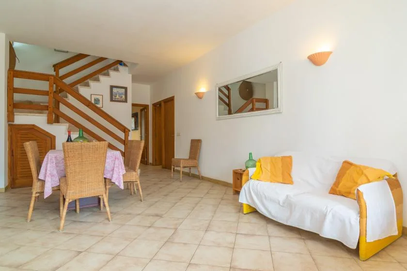 Una sala de estar con mesa de comedor, asientos y una escalera de madera.