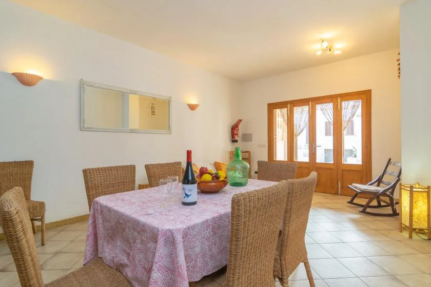 Comedor con una mesa y sillas, junto a puertas de madera con paneles de vidrio.