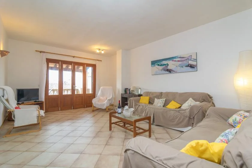 Una sala de estar con asientos alrededor de una mesa de centro de madera y grandes ventanas.
