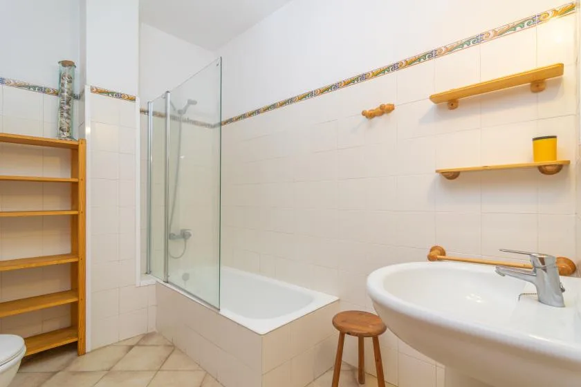 Un baño luminoso con bañera, ducha y lavabo.