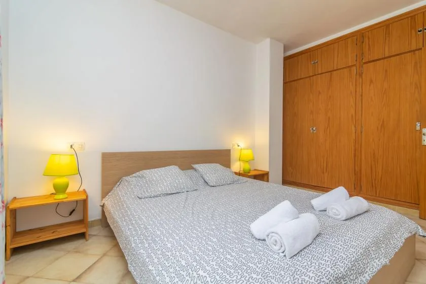 Un dormitorio con una cama, mesitas de noche y un armario de madera.