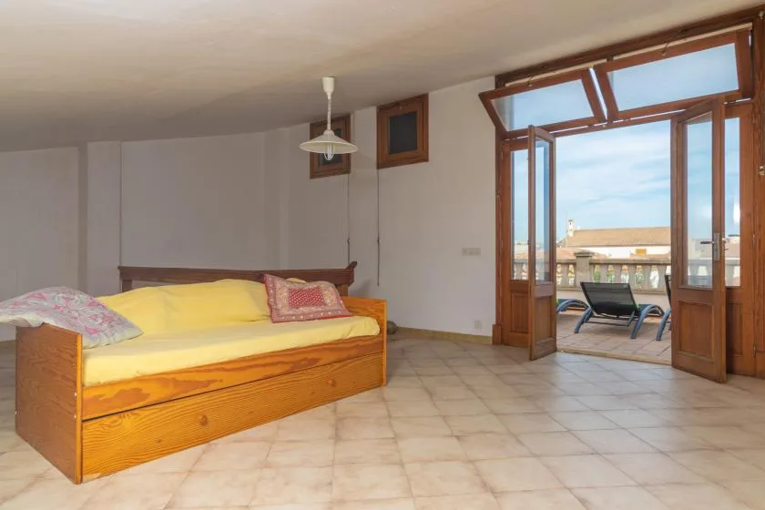 Un dormitorio con una cama de madera junto a puertas abiertas que dan a un balcón.
