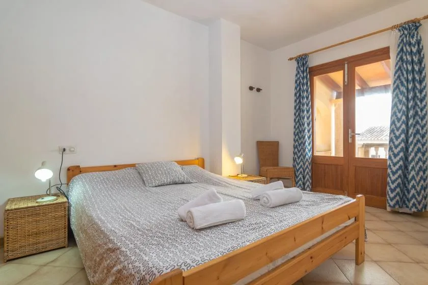 Un dormitorio con cama doble, lámparas de noche y una puerta acristalada que da a un balcón.