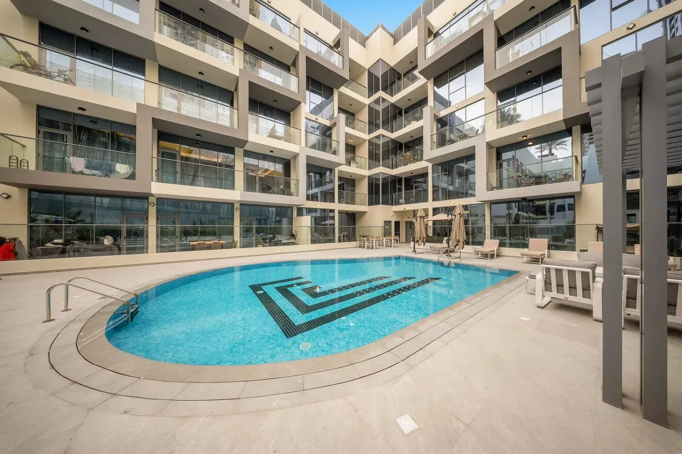 A courtyard swimming pool sits amid a modern multi-story building.