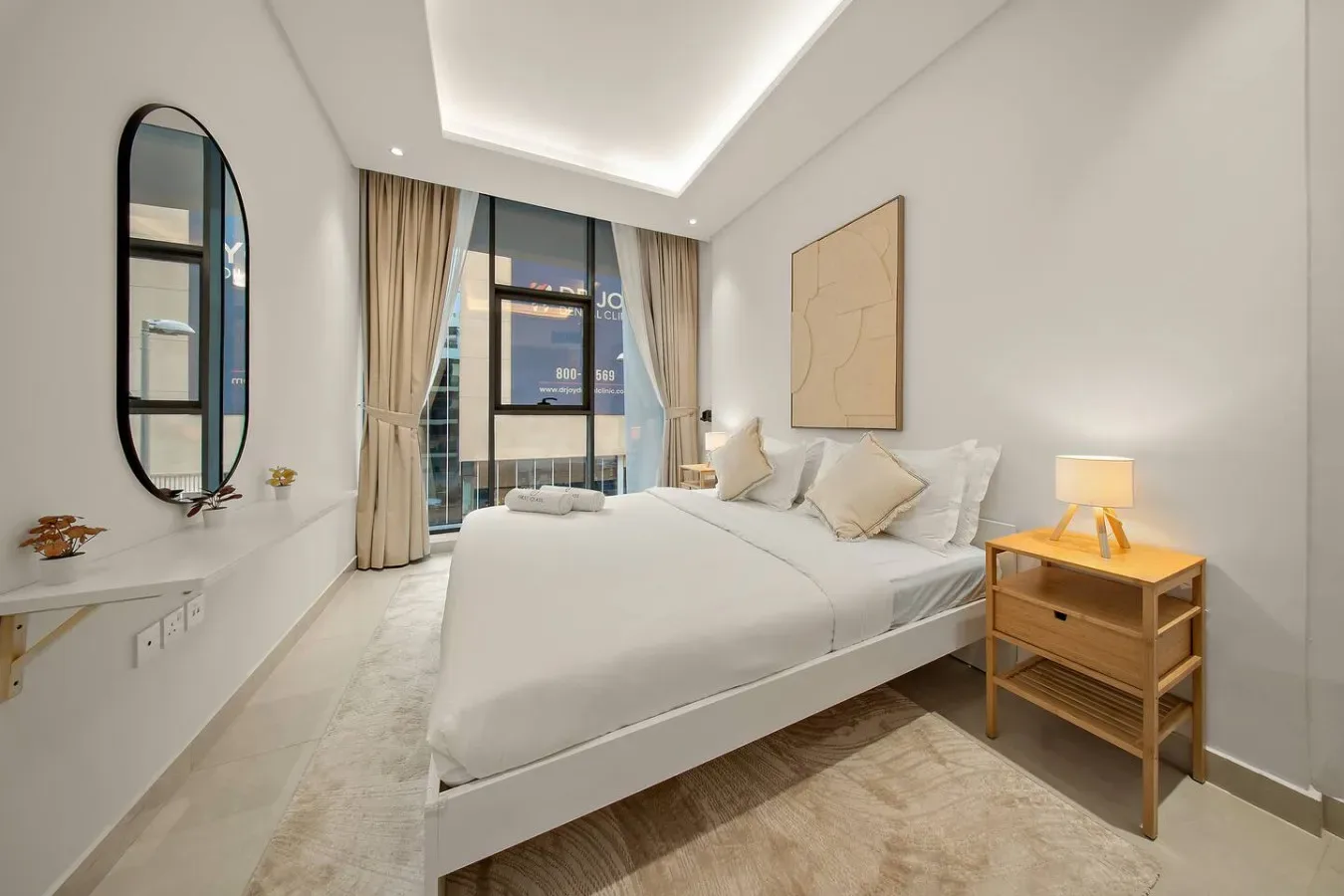 A bright bedroom with a neatly made bed beside a large window.