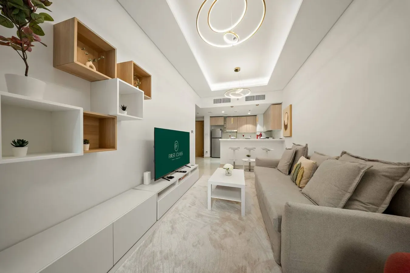 A bright living room with a sectional sofa, coffee table, and open kitchen.