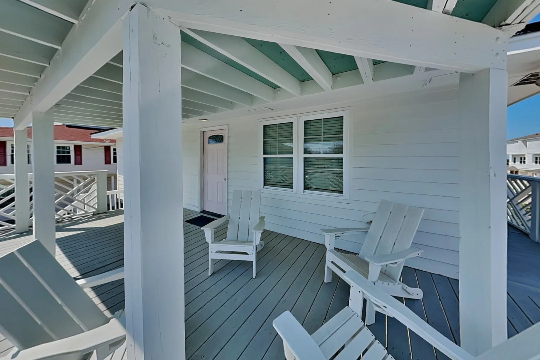 A covered porch with white seating beside a window.