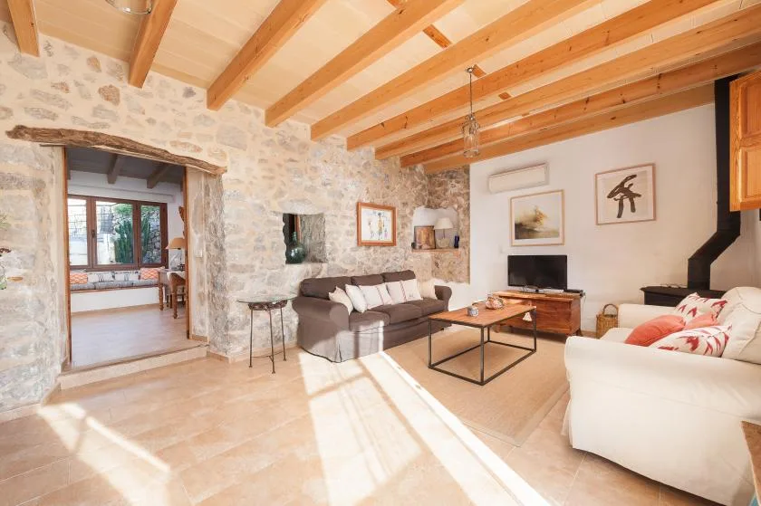 A living room with seating, a coffee table, and exposed wooden ceiling beams.