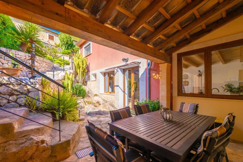A shaded outdoor dining area with a table beside a garden courtyard.