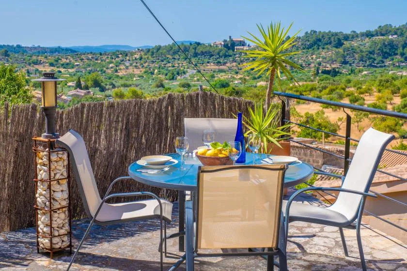 Una zona de comedor al aire libre con mesa, asientos y vistas a las colinas.