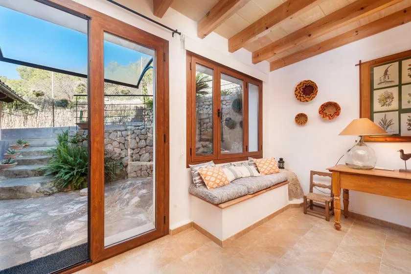A bright sitting area with a cushioned bench beside large glass doors.