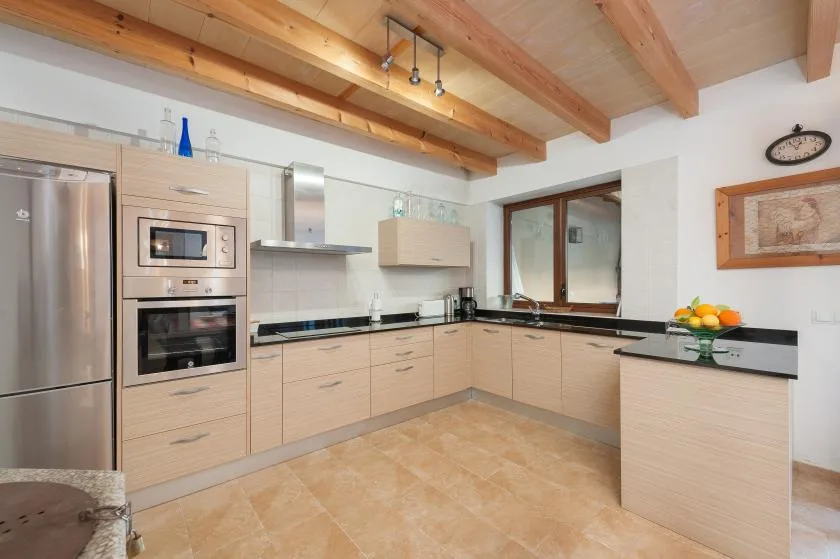 A bright kitchen with light wood cabinets, stainless steel appliances, and a central island.