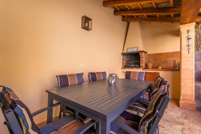 A dining area with a long table and seating beside a tiled kitchen counter.