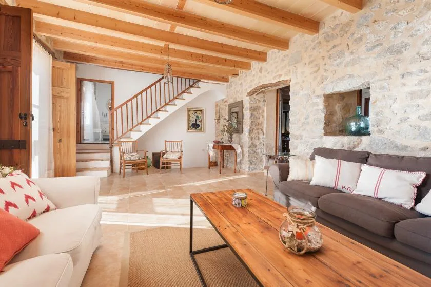 A bright living room with seating, a wooden coffee table, and an exposed-beam ceiling.