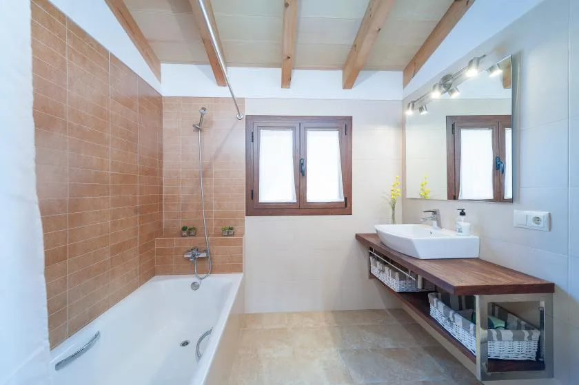 A bright bathroom with a bathtub, sink, and large wall mirror.