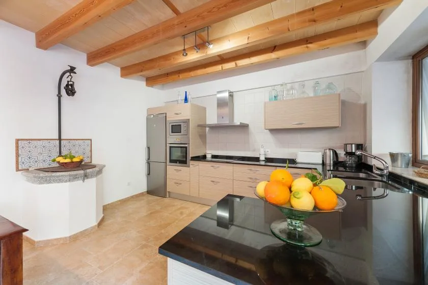 A bright kitchen with light cabinets and a fruit bowl on the counter.