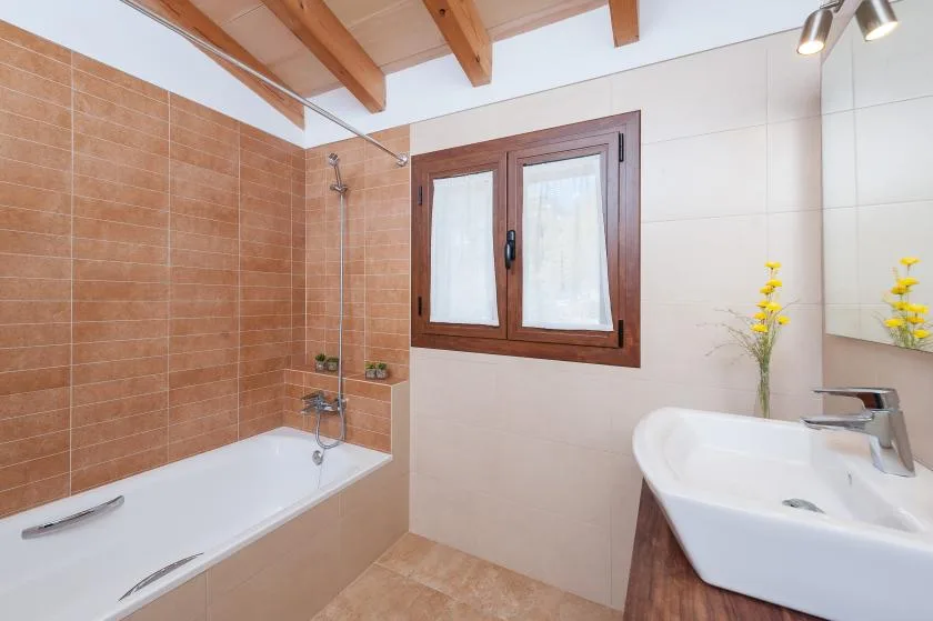 A bathroom with a bathtub, shower, window, and sink.