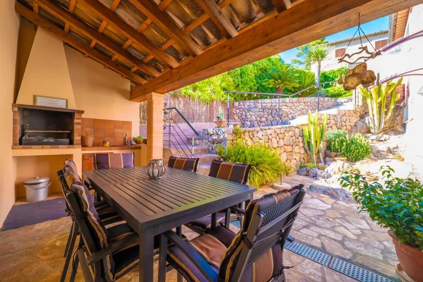 A covered outdoor dining area opens onto a landscaped stone courtyard.