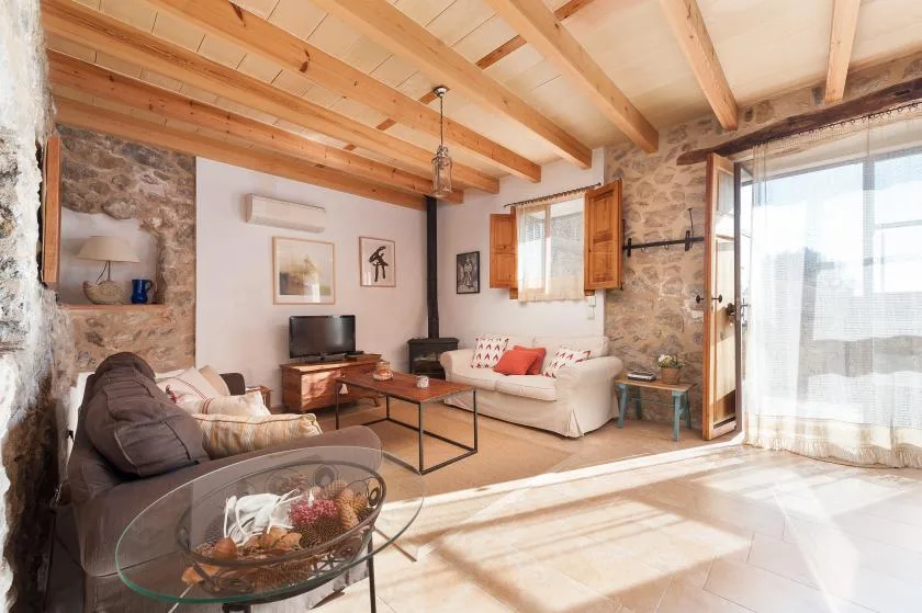A bright living room with seating, a coffee table, and exposed wooden ceiling beams.