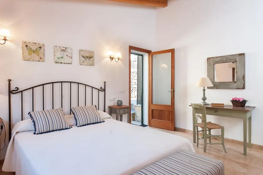 A bedroom with a bed, an open wooden door, and a writing desk.