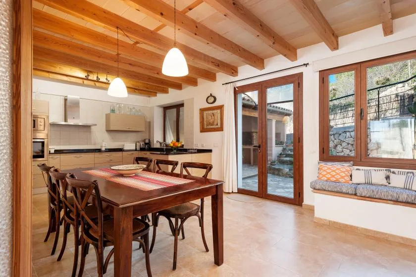 A dining area with a wooden table beside a kitchen and large glass doors.