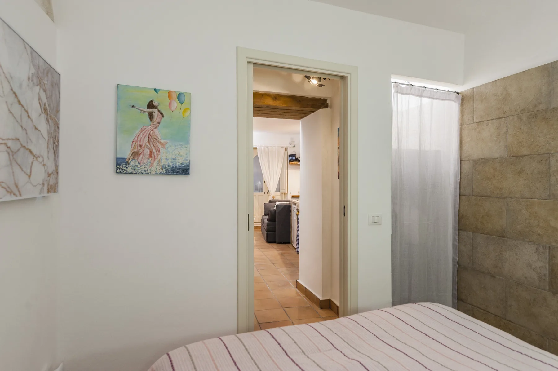 Un dormitorio con una puerta que da a un pasillo con suelo de baldosas.