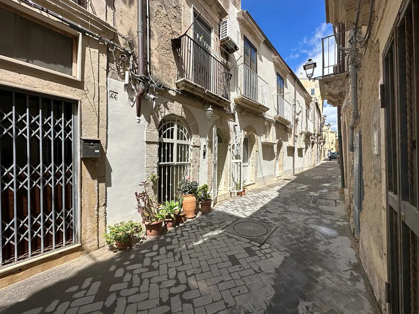 Una calle estrecha empedrada discurre entre edificios muy próximos bajo el sol.