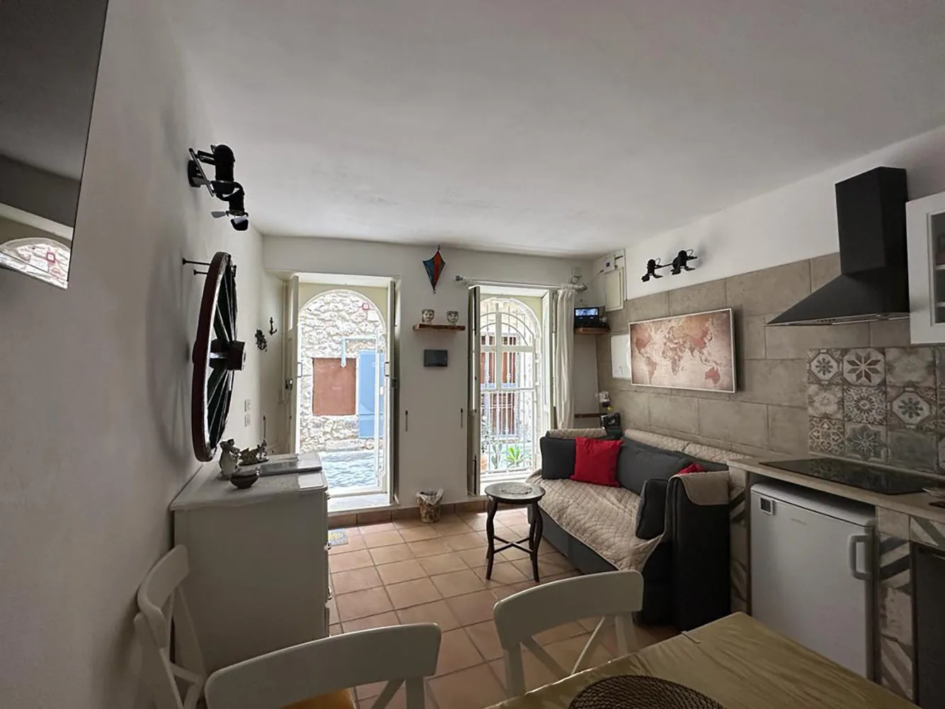 Una cocina compacta y una zona de estar con suelo de baldosas y una mesa pequeña.