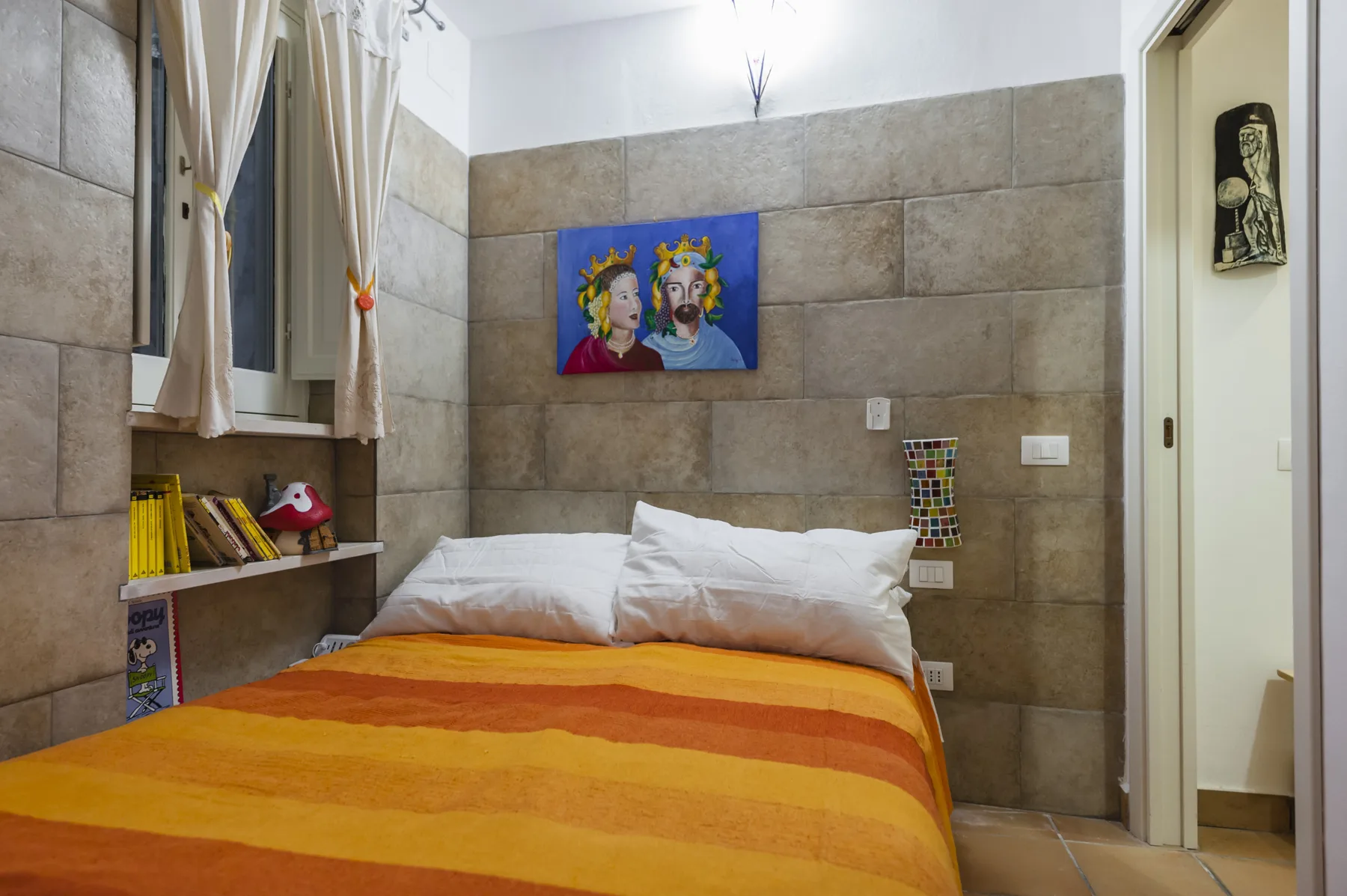 Un dormitorio con una cama cubierta con ropa de cama a rayas naranjas y amarillas.