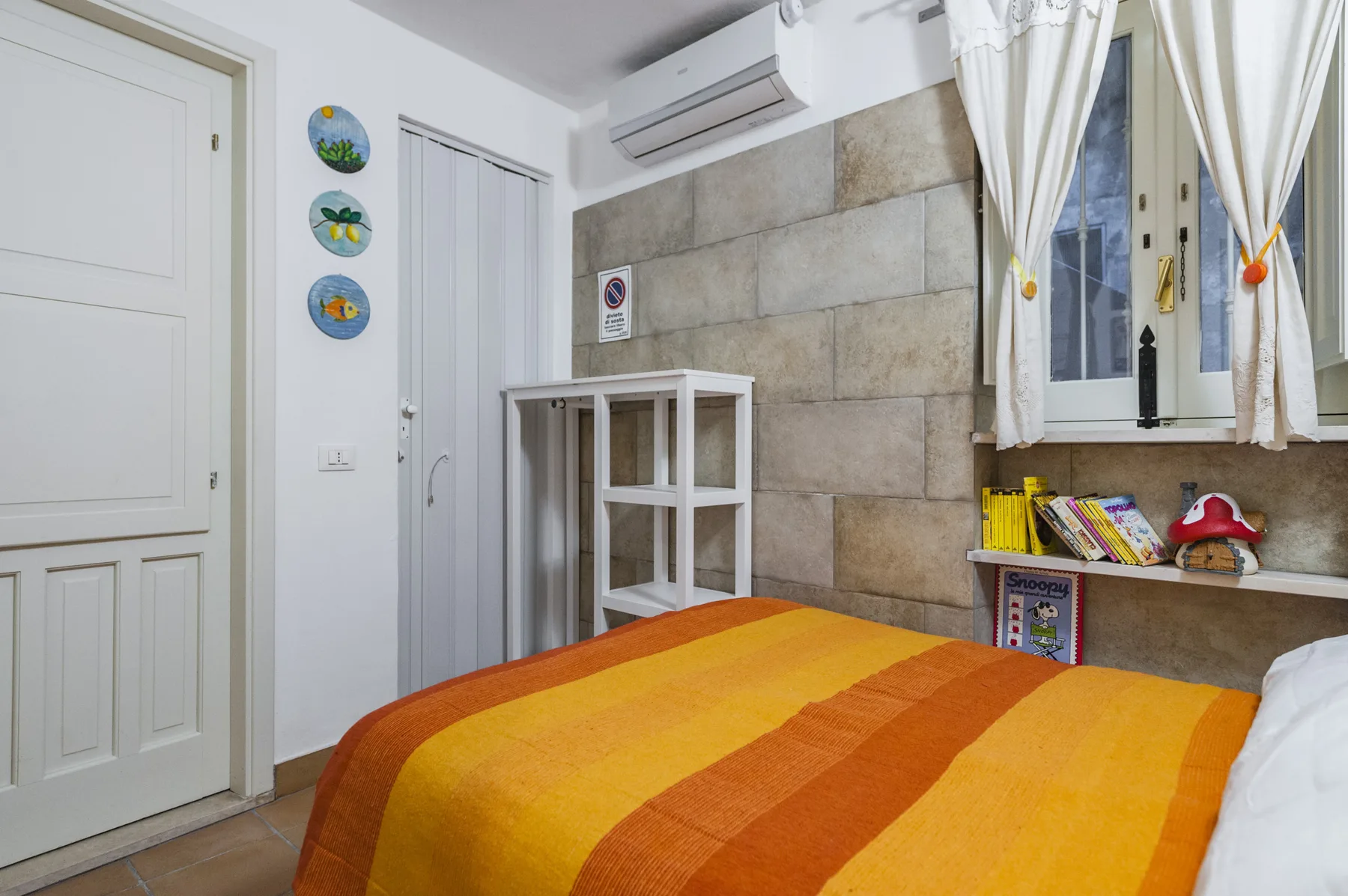 Un dormitorio con una cama cubierta por una colcha a rayas naranjas y amarillas.