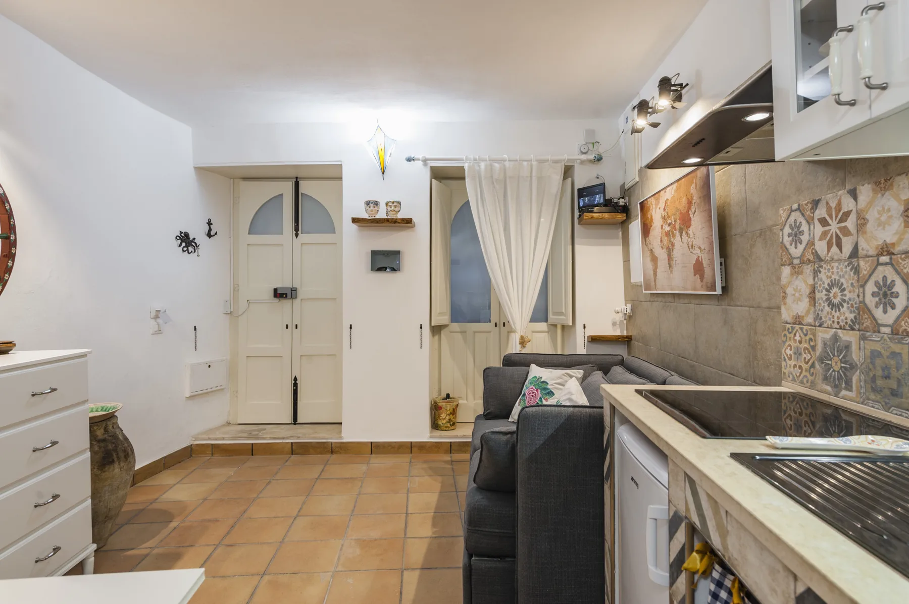 Una pequeña zona de estar con un sofá junto a una encimera de cocina.