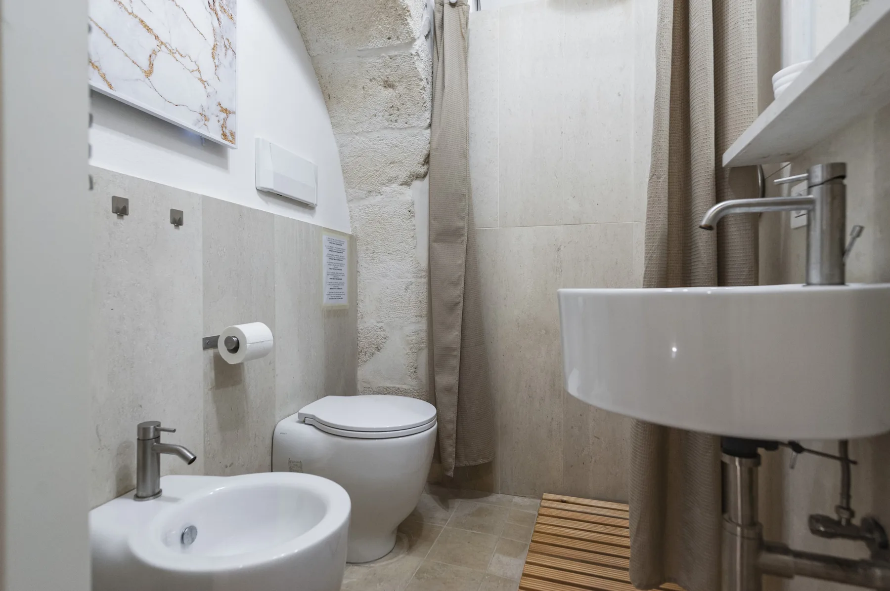 Un baño con inodoro, bidé y lavabo junto a una cortina de ducha.