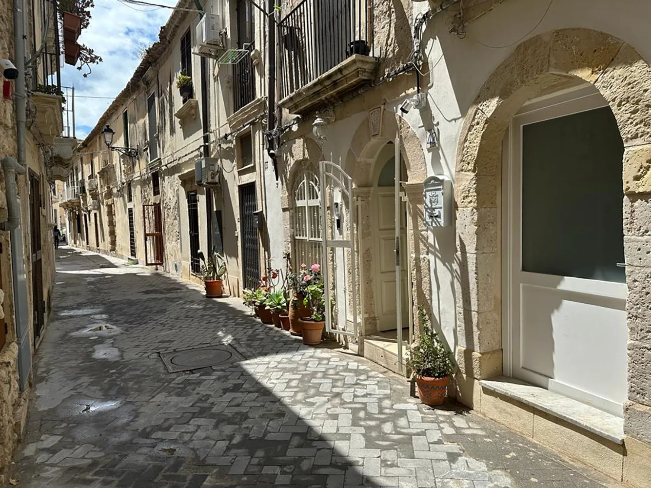 Una calle estrecha empedrada pasa entre edificios de piedra muy juntos bajo el sol.