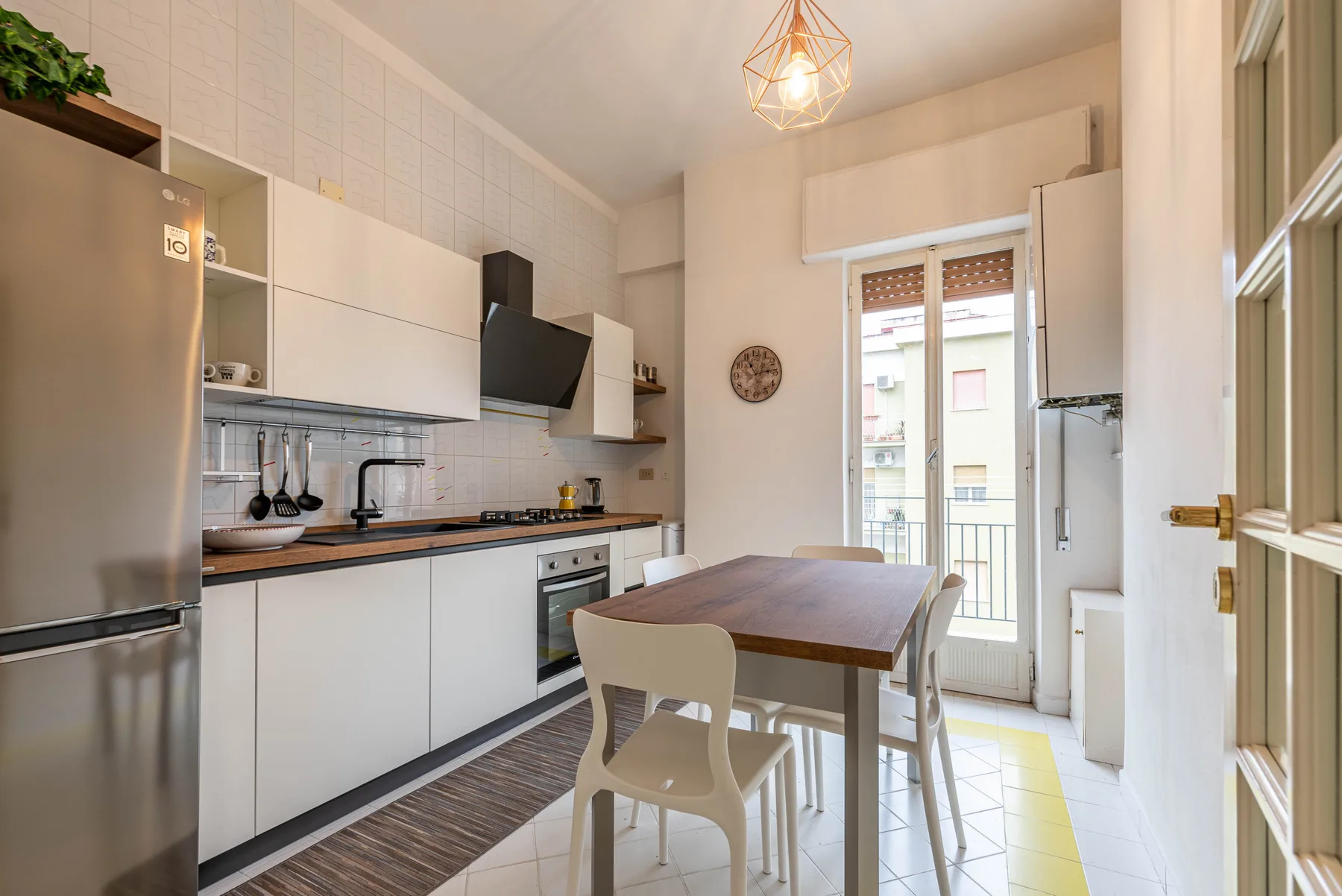 A bright kitchen and dining area with white cabinetry and a table by the balcony doors.