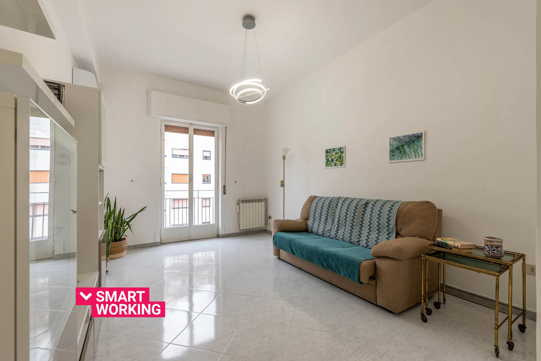 A bright living room with a teal-covered sofa and tall windows.