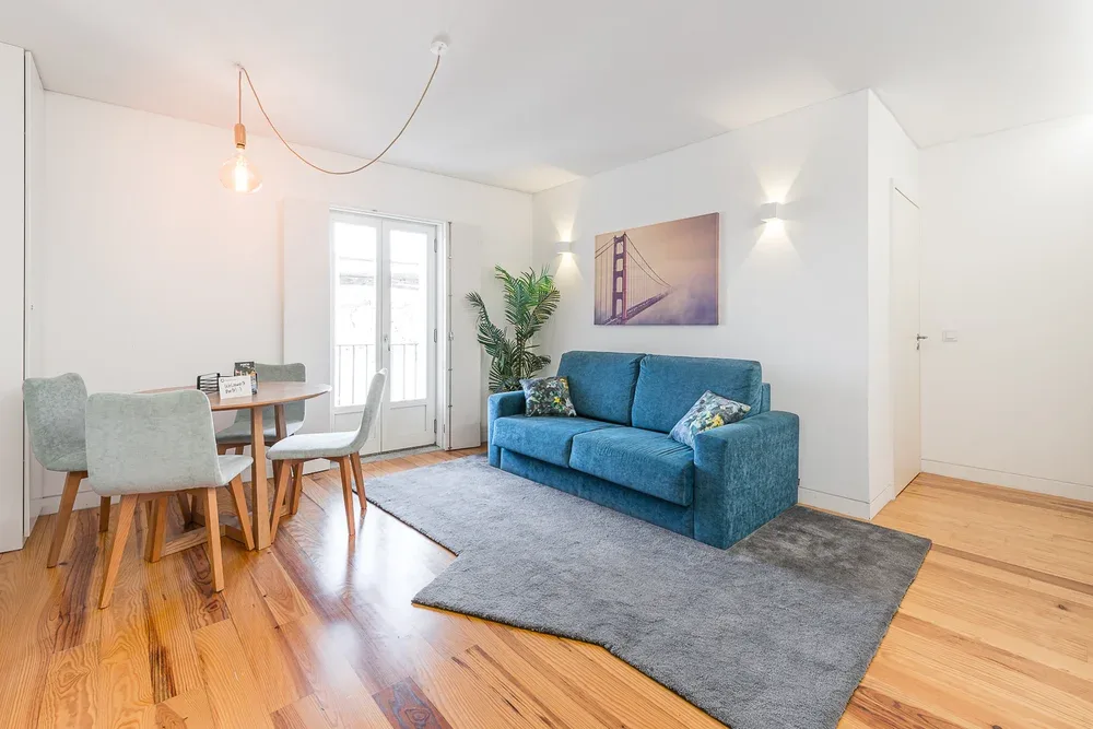A bright living and dining area with blue seating beside a dining table.