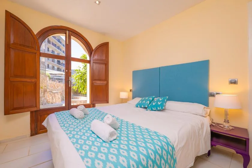 A bedroom with a large arched window and turquoise bedding.