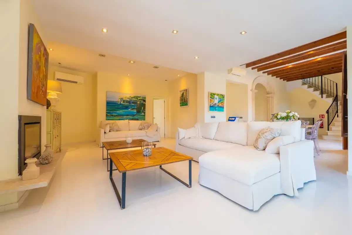 A bright living room with white seating and a wooden coffee table.