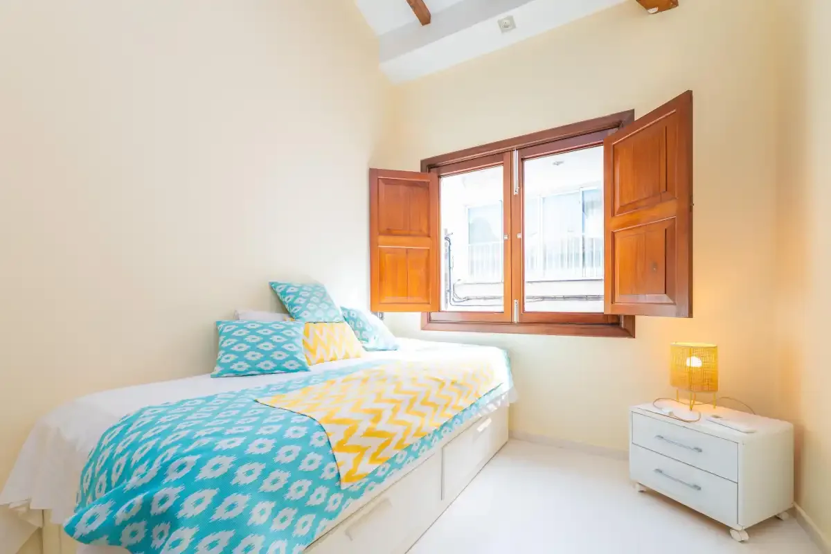 A bedroom with a bed beside an open window.