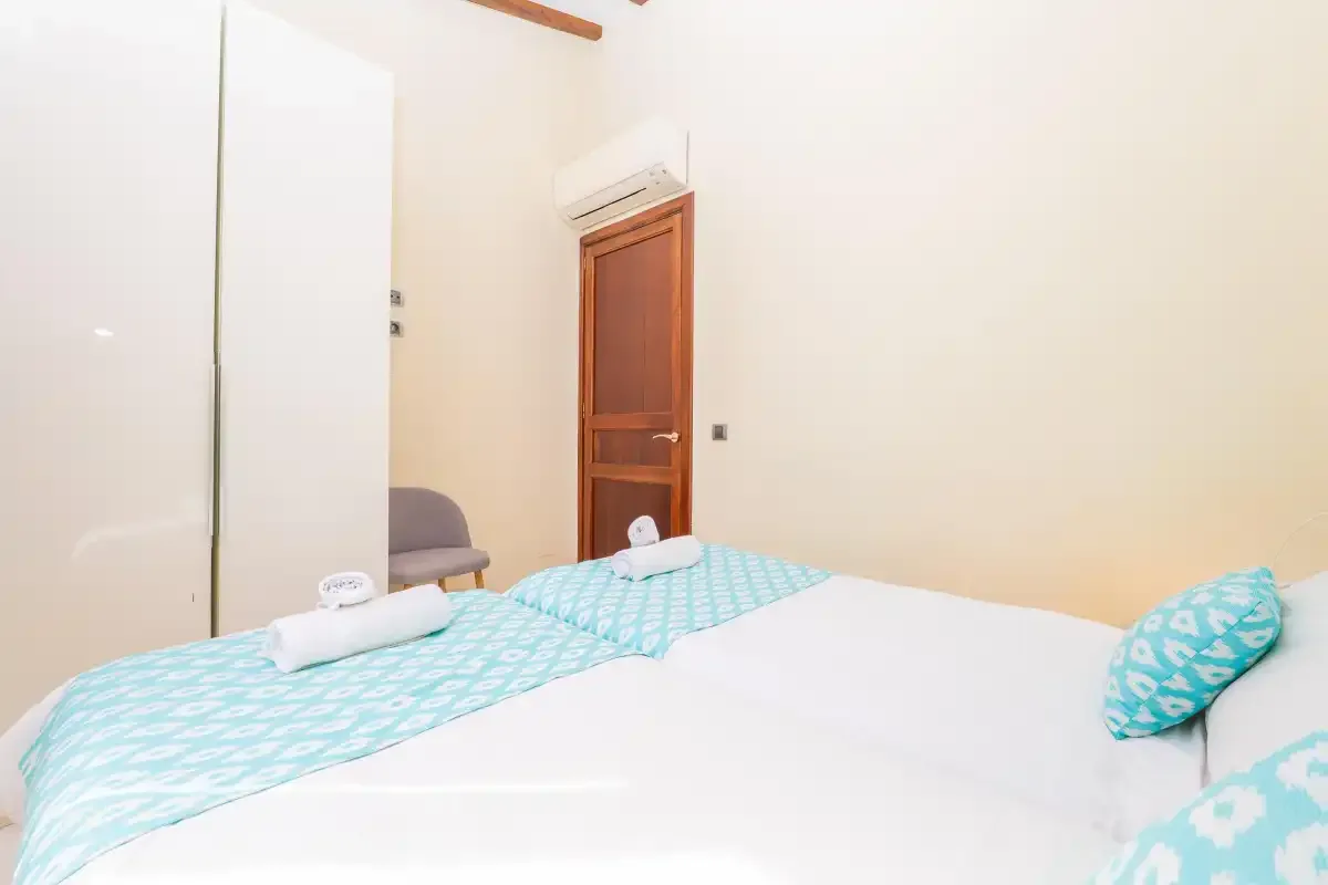 A bedroom with a bed dressed in turquoise-patterned bedding.