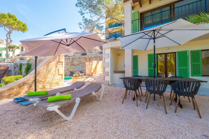 An outdoor patio with lounge seating, dining furniture, and umbrellas beside a building.