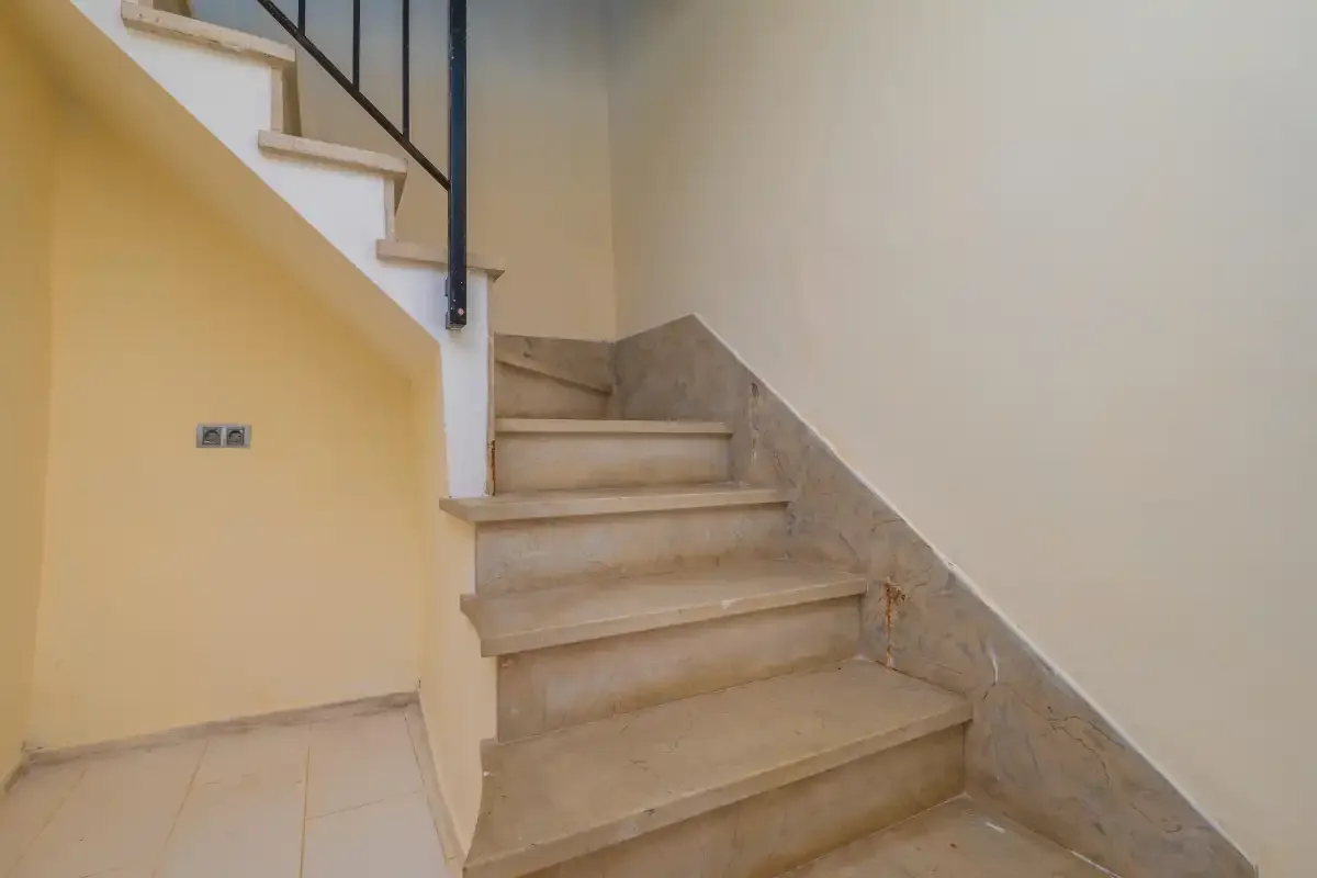 An indoor staircase with pale stone steps and a dark railing.
