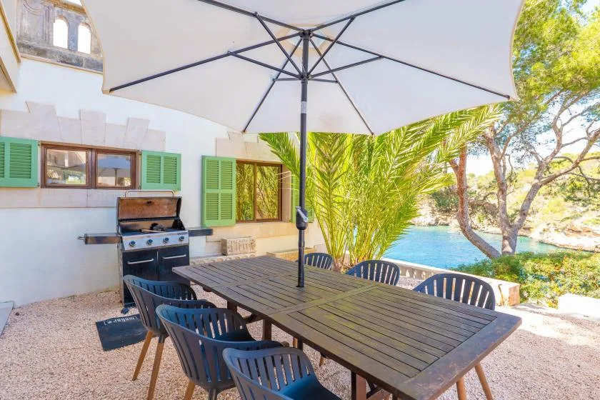 An outdoor patio with a long table and umbrella overlooks a swimming pool.