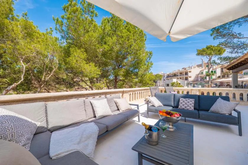 An outdoor terrace with cushioned seating and a table beneath an umbrella.