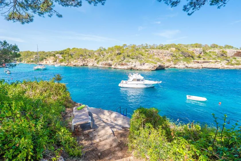 A coastal cove with boats on the water and greenery along the shore.