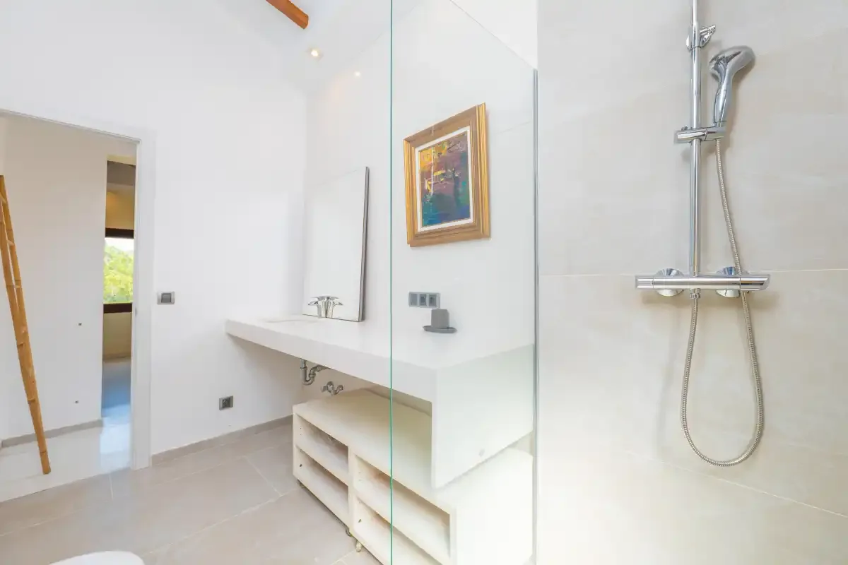 A bright bathroom with a long vanity and a glass shower.