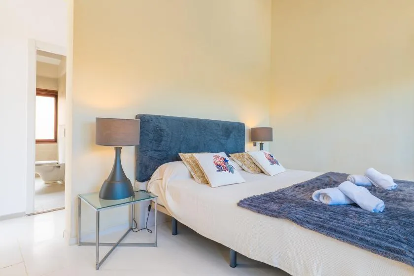 A bedroom with a bed, blue headboard, and bedside lamps.