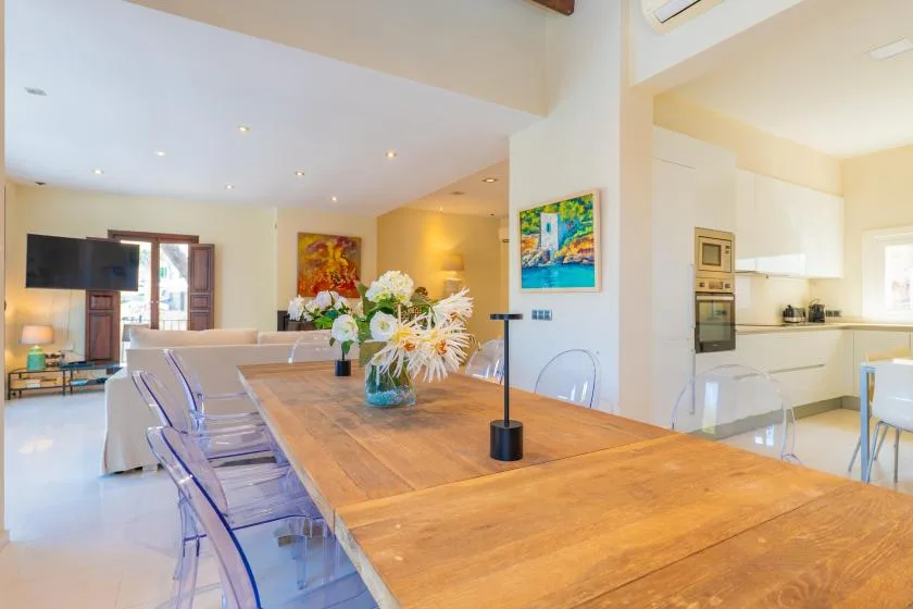 An open-plan dining area with a wooden table and a kitchen beyond.