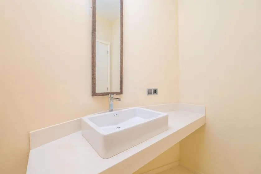 A bathroom vanity with a white vessel sink and wall mirror.
