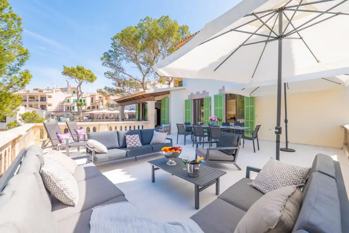 A sunny outdoor patio with seating, tables, and a large umbrella.